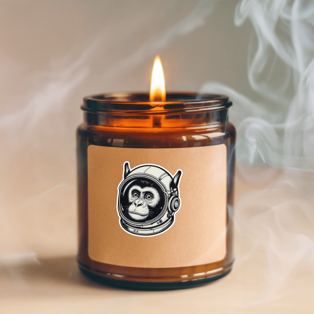 Candle in an amber jar with a sticker featuring a monkey in an astronaut helmet, emitting smoke. Durable vinyl, die-cut Astro Monkey Sticker.