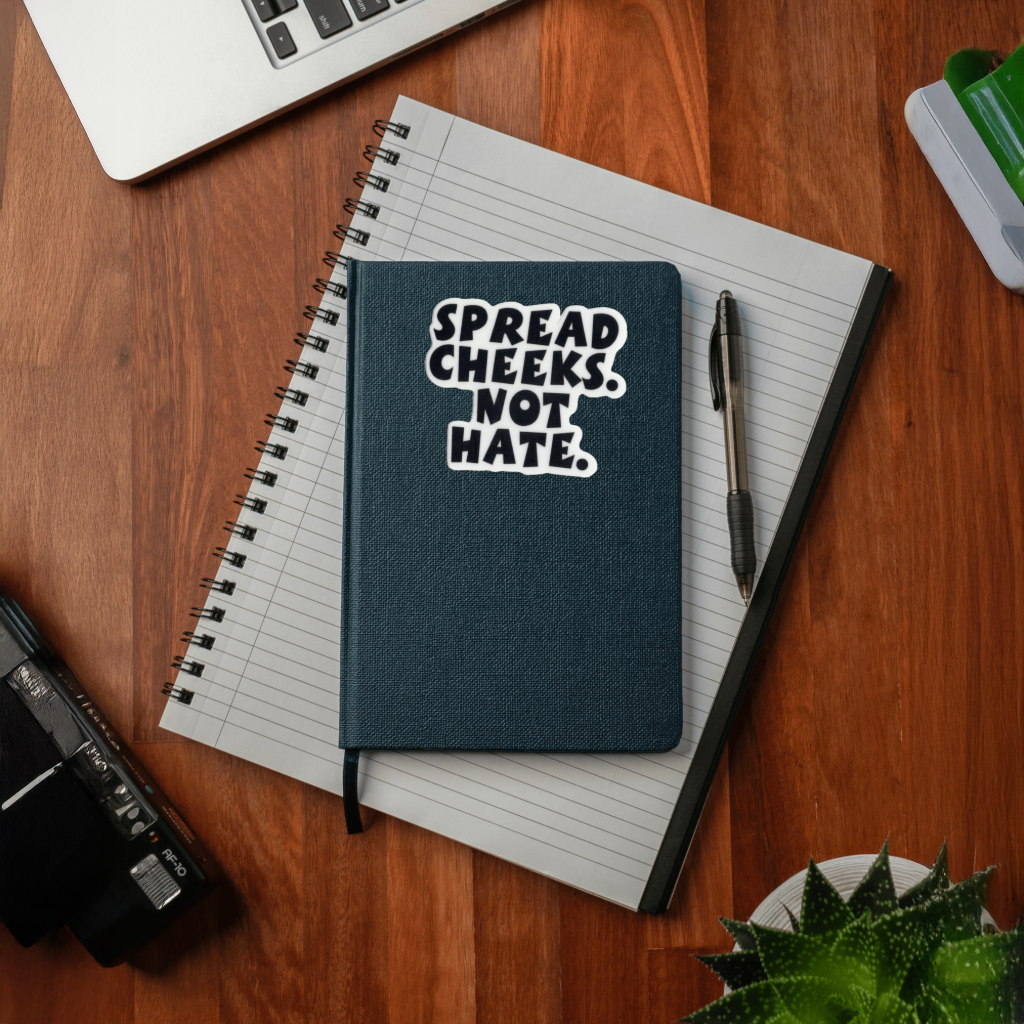 Notebook with 'Spread Cheeks, Not Hate' sticker. Durable vinyl, die-cut sticker.