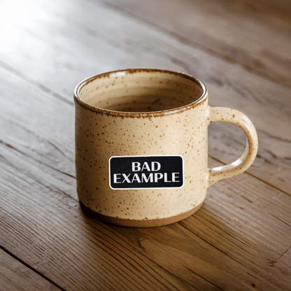 Beige ceramic mug with 'BAD EXAMPLE' sticker.  Durable vinyl, die-cut sticker.