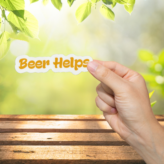 Hand holding a sign that reads 'Beer Helps' against a natural background with greenery.