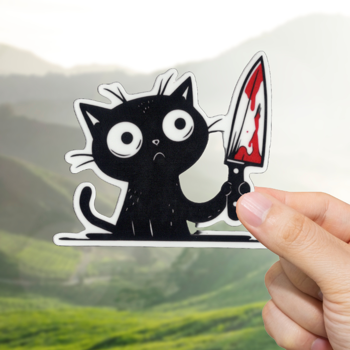 Hand holding a sticker of a black cat with a knife over a scenic background