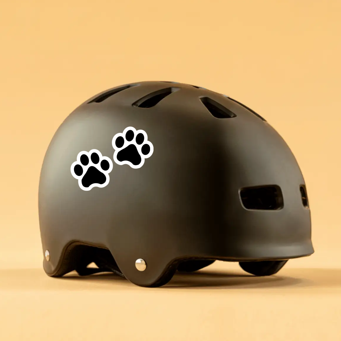 Black helmet with paw print decals on a beige background