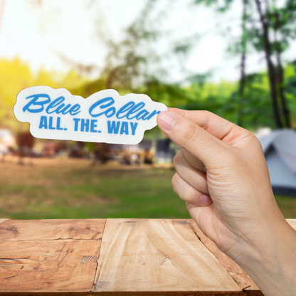 Hand holding a 'Blue Collar All. The. Way' sticker with a blurred outdoor background
