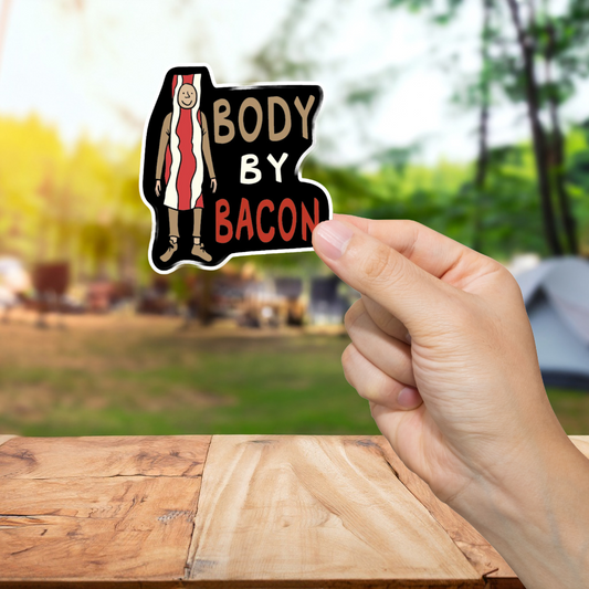 Hand holding a 'Body by Bacon' sticker with a blurred outdoor background