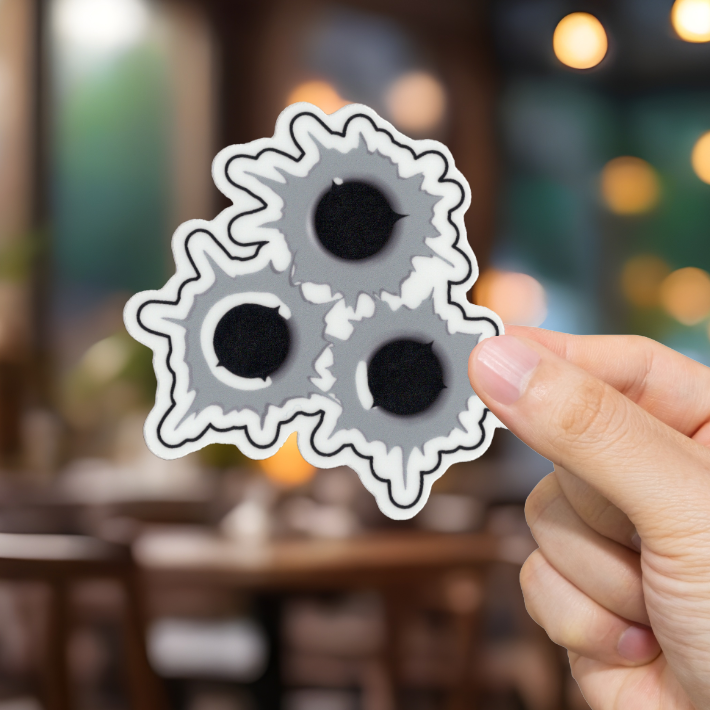 Hand holding a sticker with bullet holes in a blurred restaurant setting