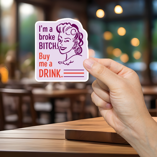 Hand holding a card with text in a restaurant setting. I'm a Broke Bitch.  Buy me a drink!