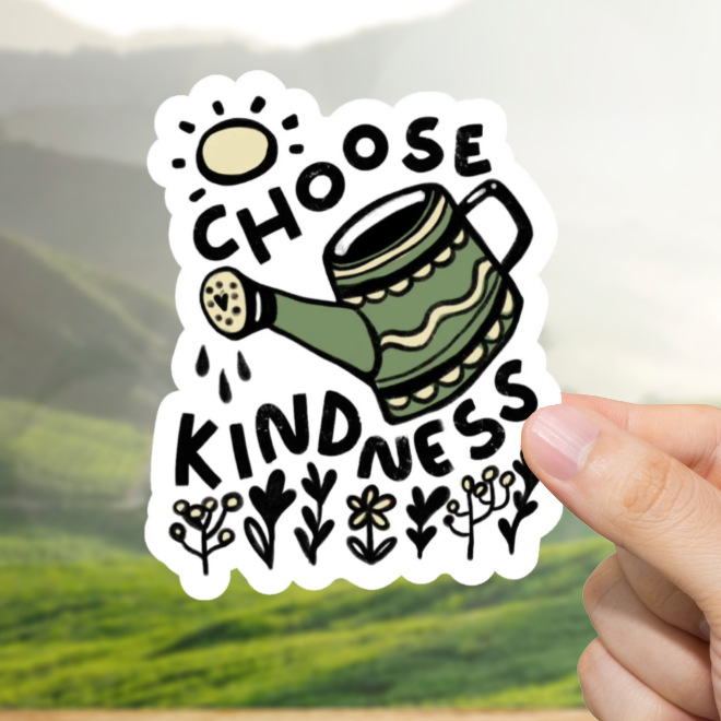 Hand holding a sticker with 'Choose Kindness' text against a scenic background