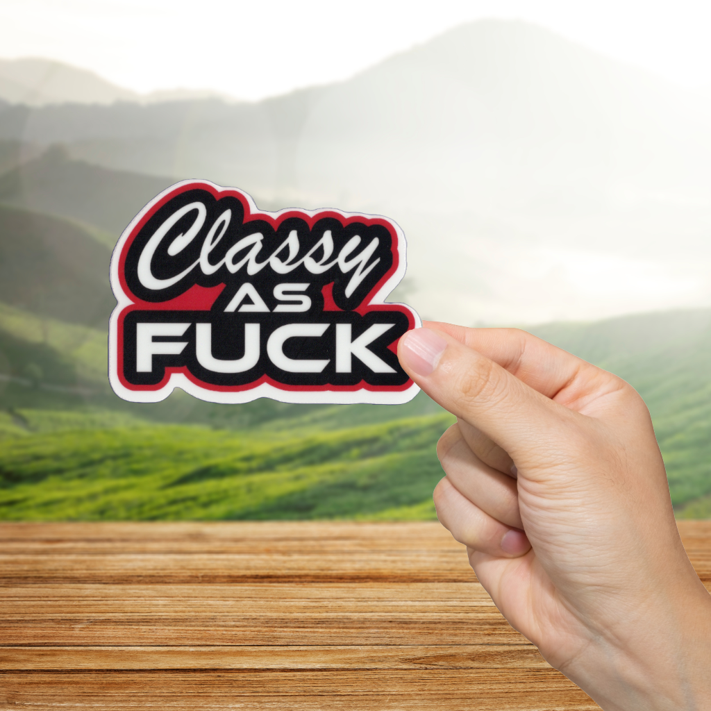 Hand holding a 'Classy as Fuck' sticker with a scenic background