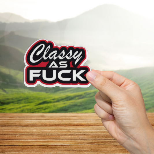 Hand holding a 'Classy as Fuck' sticker with a scenic background