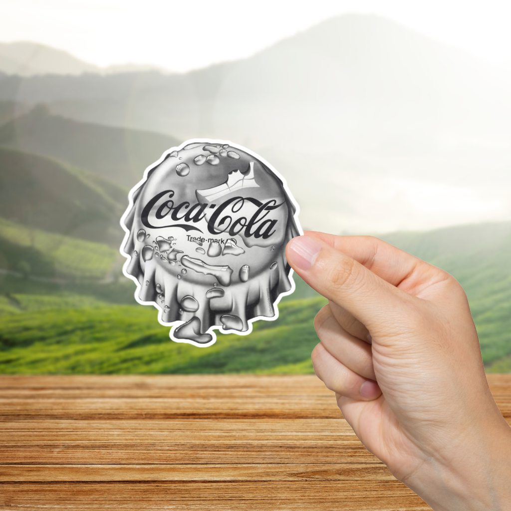 Coca-Cola bottle cap sticker held by a hand with a scenic background