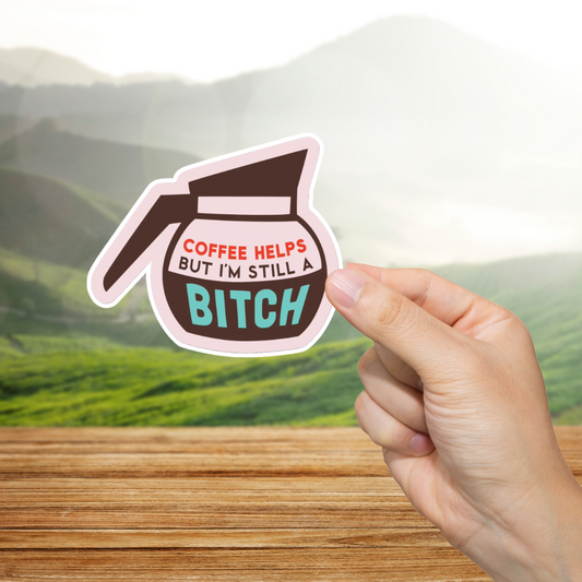 Sticker with coffee pot design and text "Coffee helps but I'm still a bitch." held by a hand against a scenic background