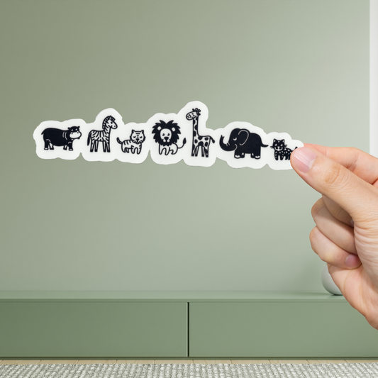 Hand holding a strip of animal stickers against a green background
