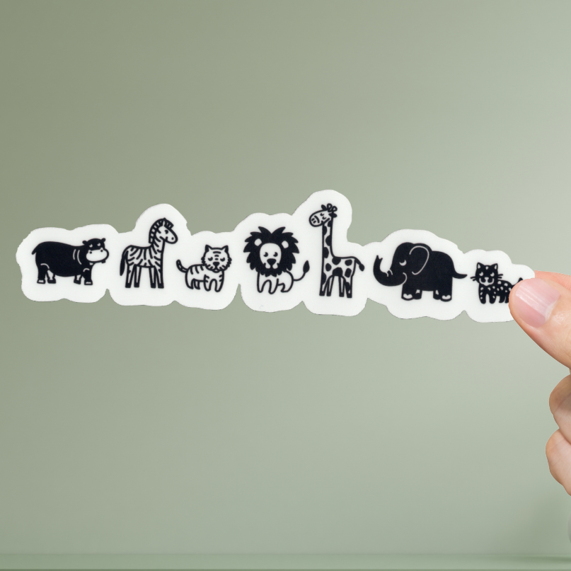 Hand holding a strip of animal stickers against a green background