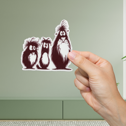 Hand holding a sticker of three cartoon-like dogs against a green background