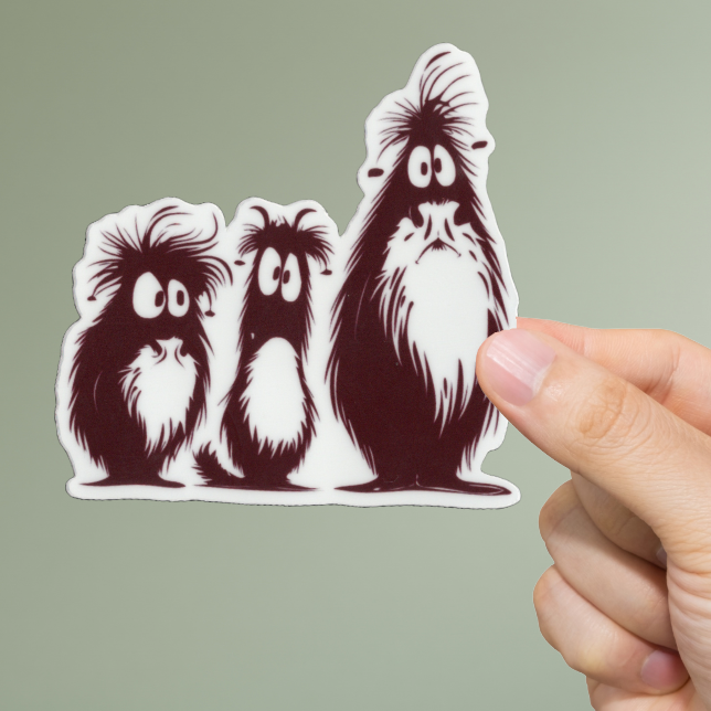 Hand holding a sticker of three cartoon-like dogs against a green background