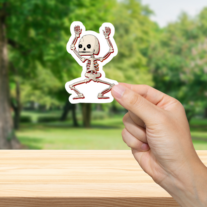 Hand holding a dancing skeleton sticker with a blurred green outdoor background