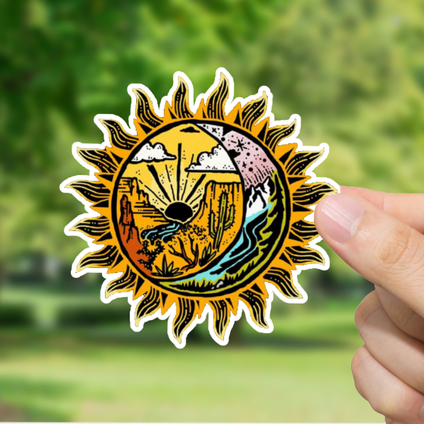 Hand holding a sun-shaped sticker with nature design against a blurred green outdoor background