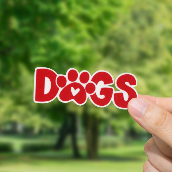 Hand holding a 'DOGS' sign with a blurred park background