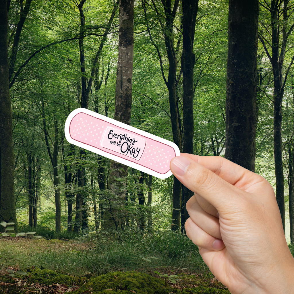 Hand holding a bandage with 'Everything will be okay' text against a forest background