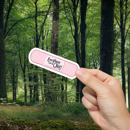 Hand holding a bandage with 'Everything will be okay' text against a forest background