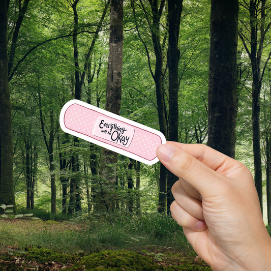 Hand holding a bandage with 'Everything will be okay' text against a forest background