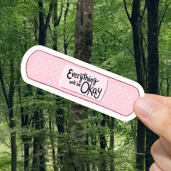 Hand holding a bandage with 'Everything will be okay' text against a forest background