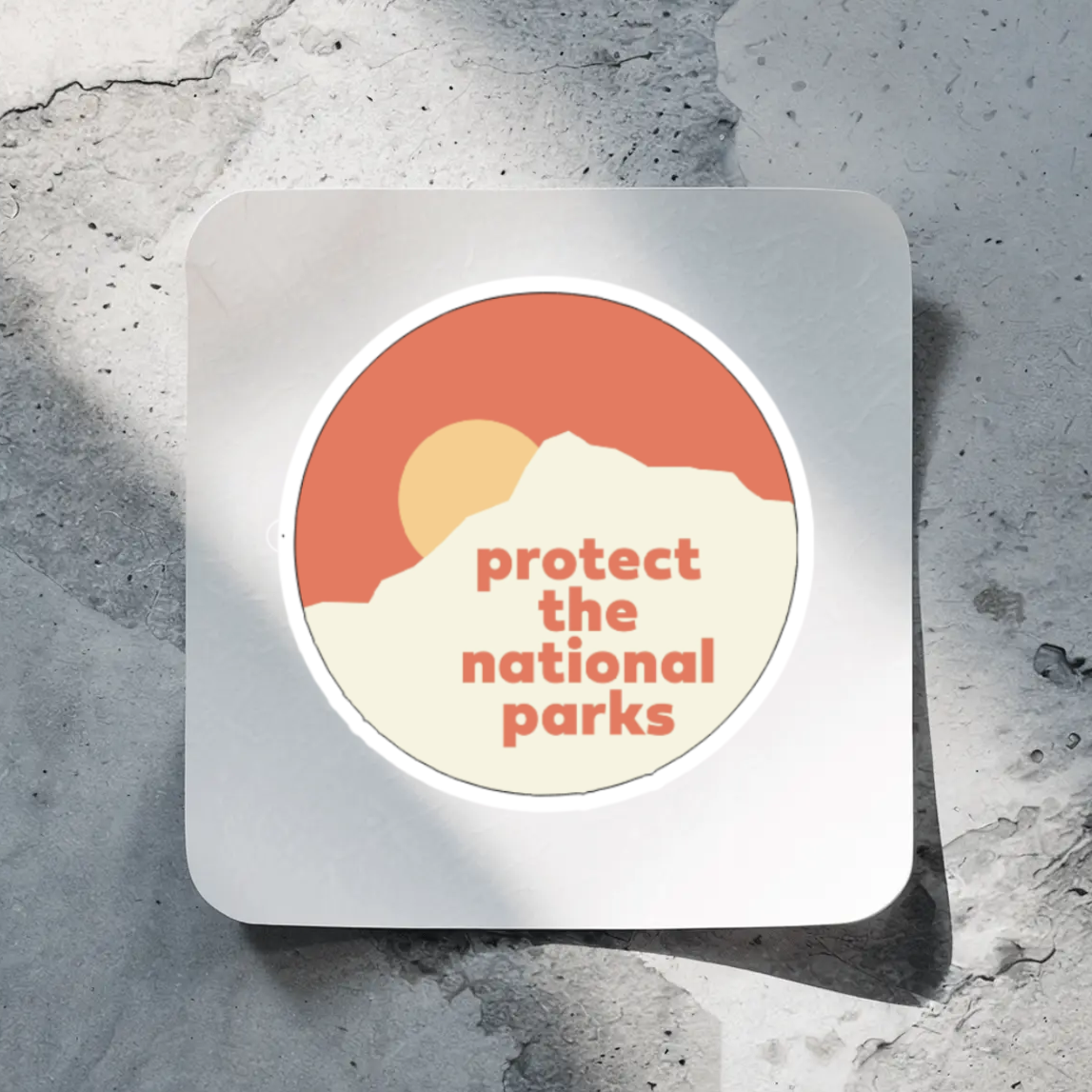 Sticker with 'protect the national parks' text on a textured surface