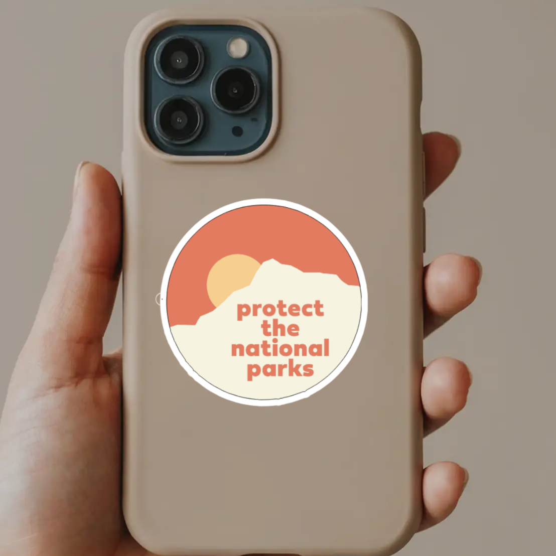 Phone case with 'protect the national parks' sticker held by a hand against a neutral background