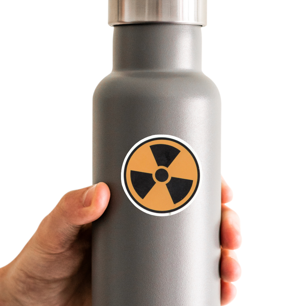 Gray water bottle with a radiation symbol sticker held by a hand on a white background